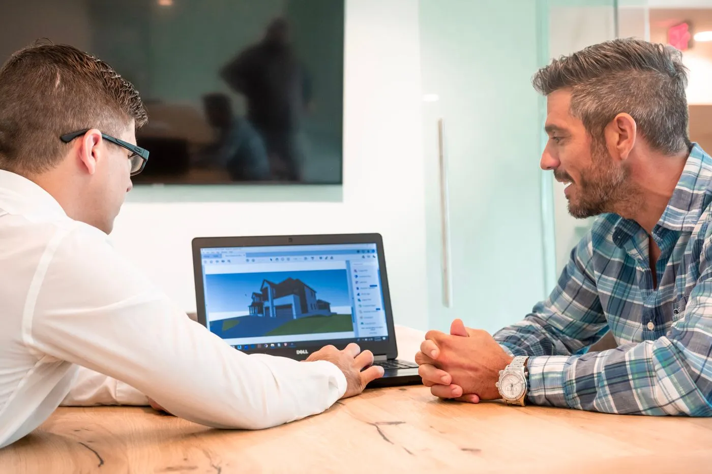 Two professionals reviewing a 3D building model on a laptop