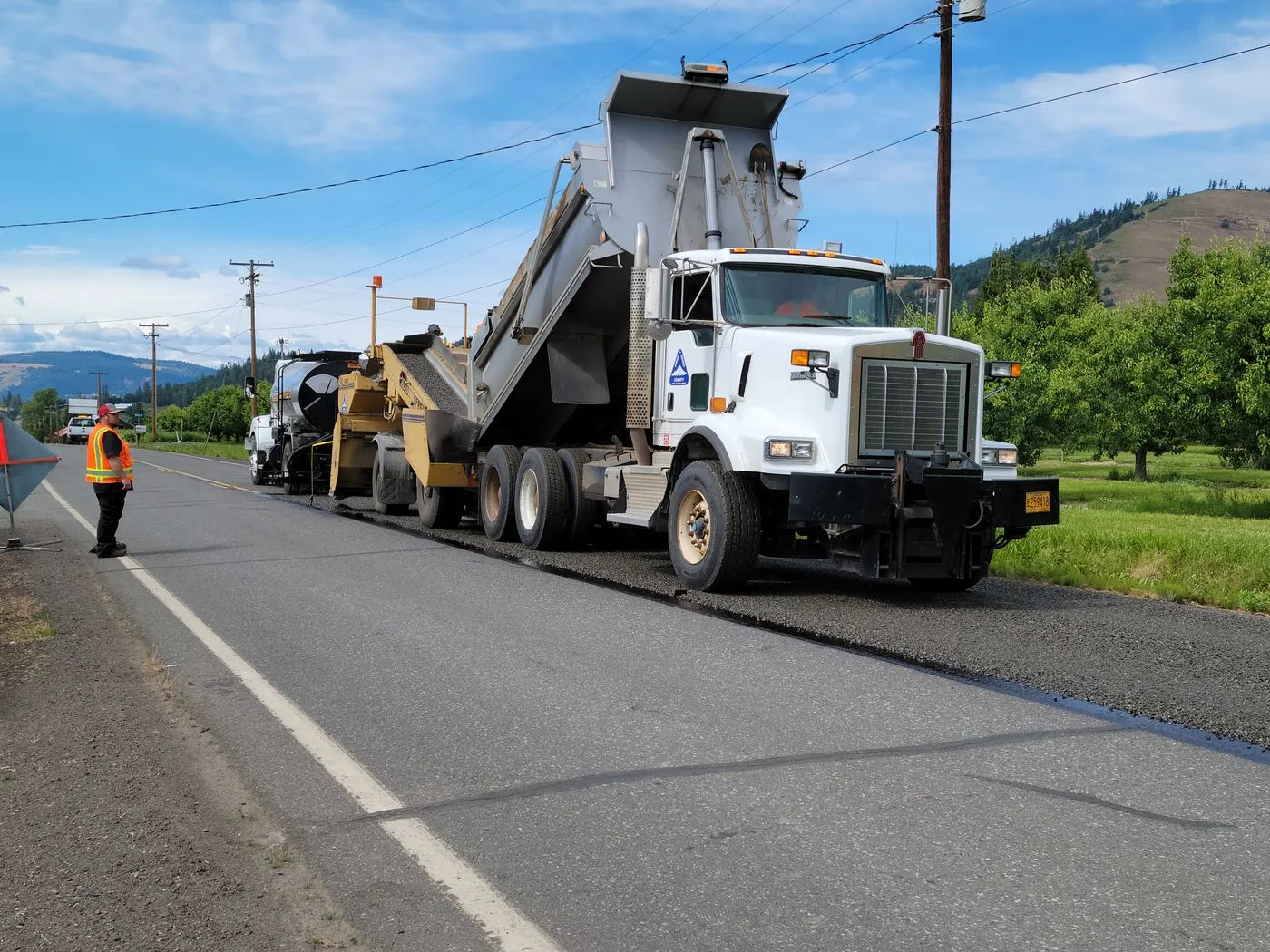 Paving crew and dump truck resurfacing a road