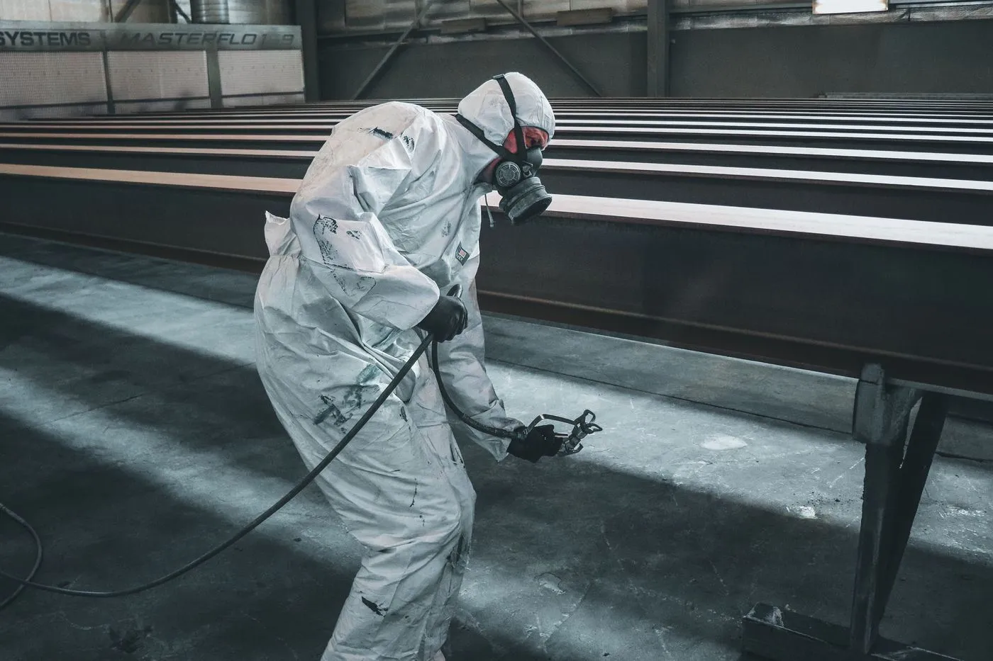 Worker spray-coating structural steel beams